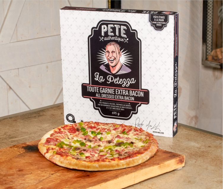 Une pizza toute garnie avec extra bacon sortant du four, présentée sur une planche en bois devant son emballage en carton